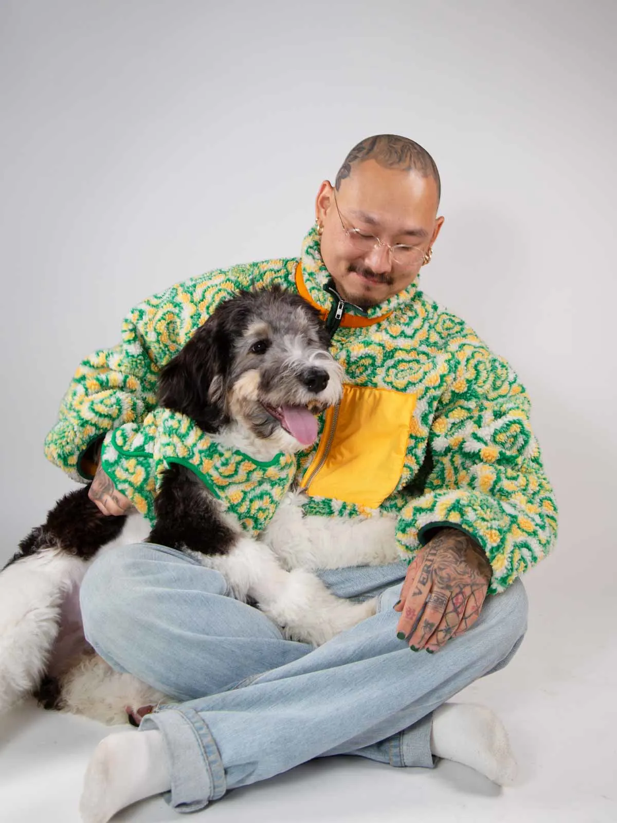 man with tattoos sits with dog in matching sweaters