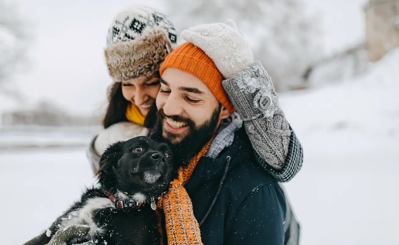 Dad and mom cuddling dog in winter