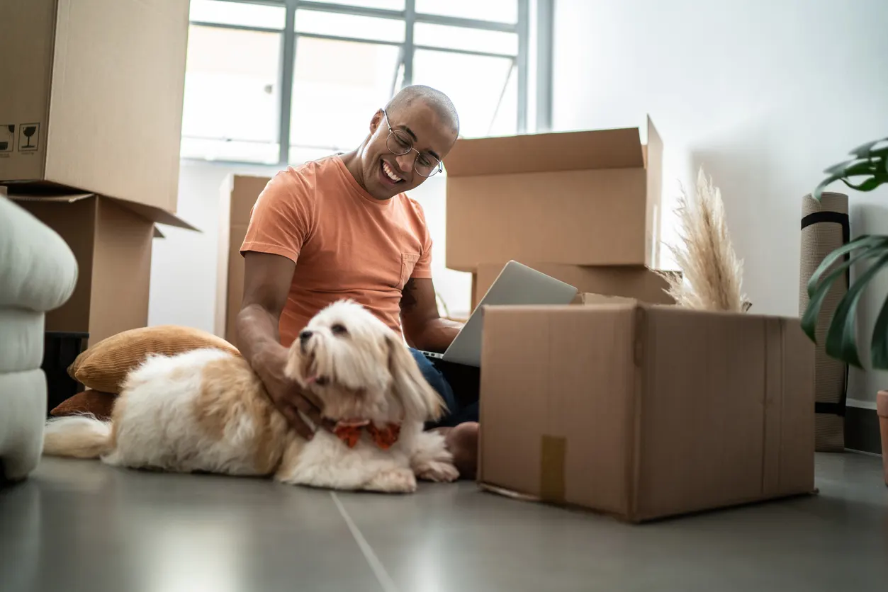 man shopping online surrounded by boxes and dog