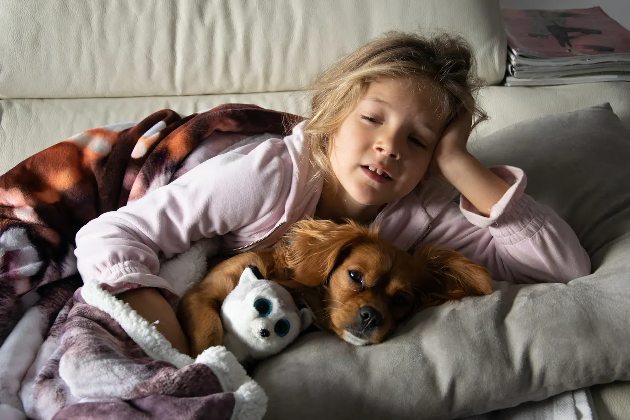 girl in bed with stuffed animal and dog