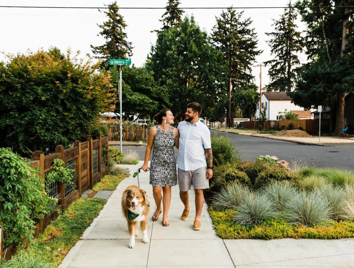 man and woman pose for photos and walk dog