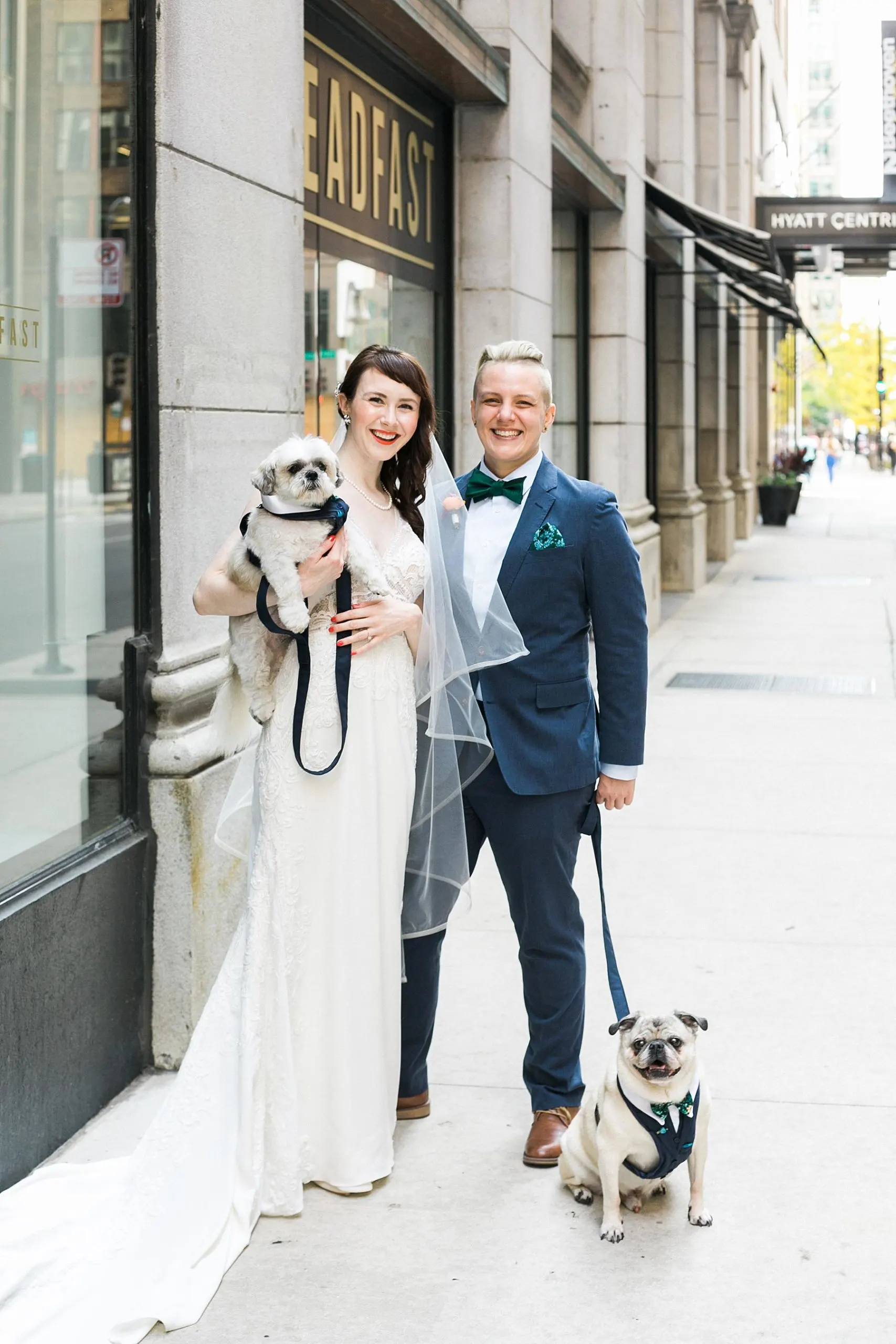couple poses on chicago street after wedding with dog