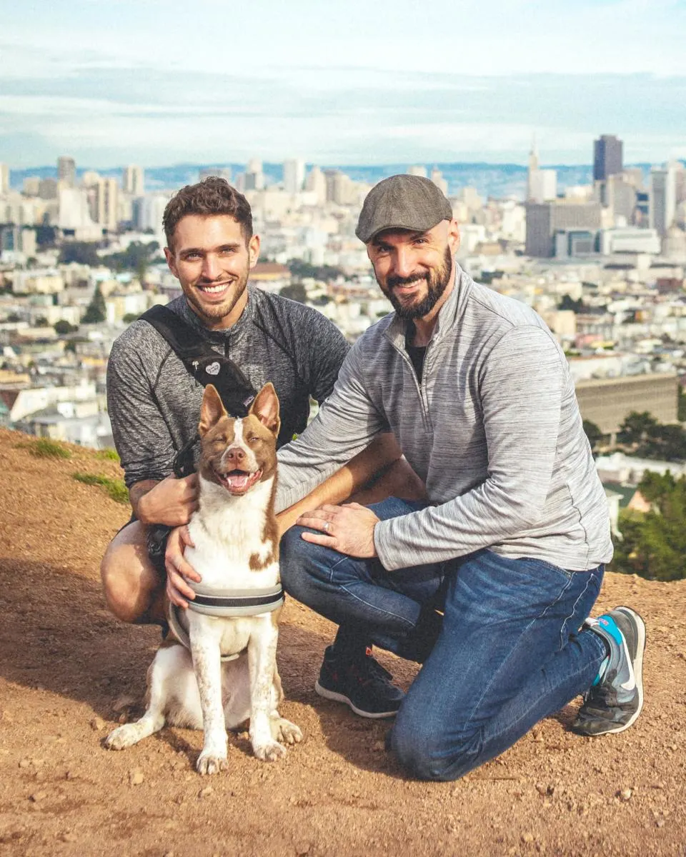Two men with their dog on a mountain