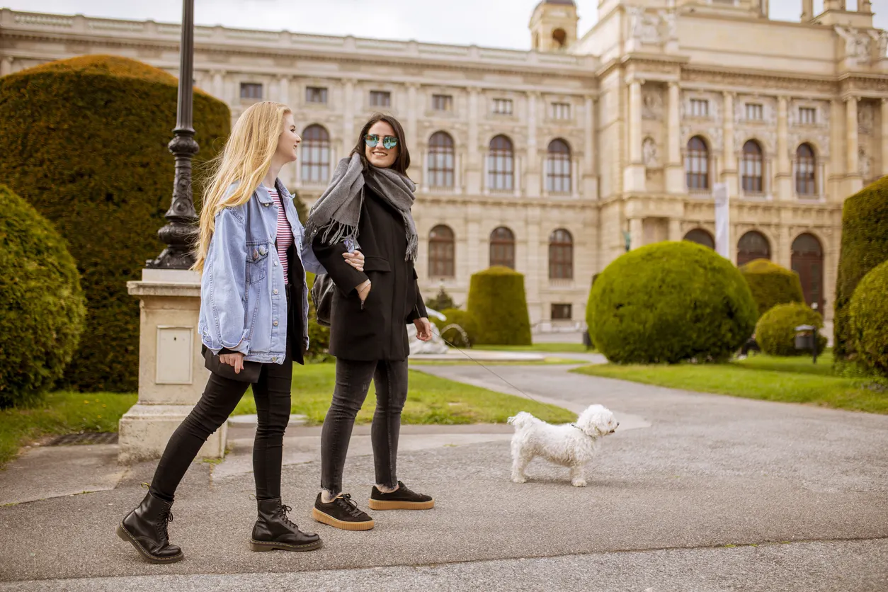 two young women walk with small dog in Vienna, Austria