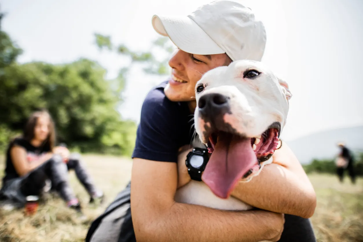 man hugs dogs outside