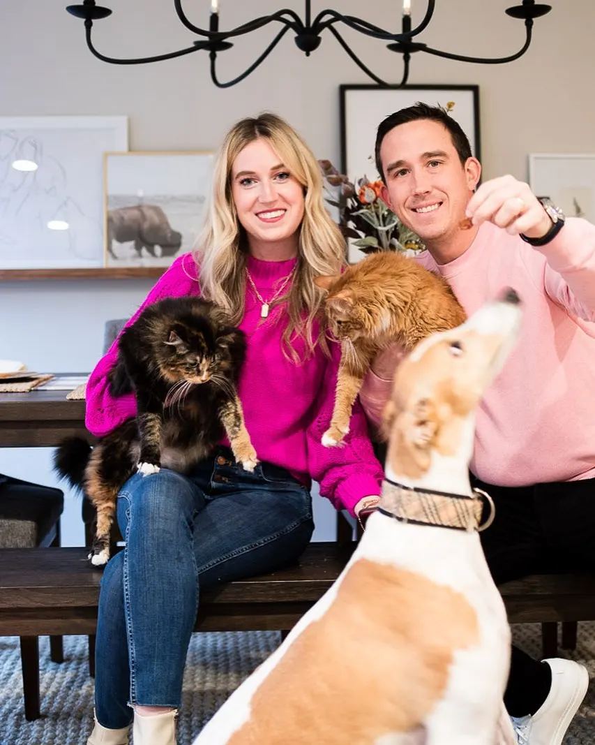 woman and man sitting with two cats and a dog posing for photo in dining room