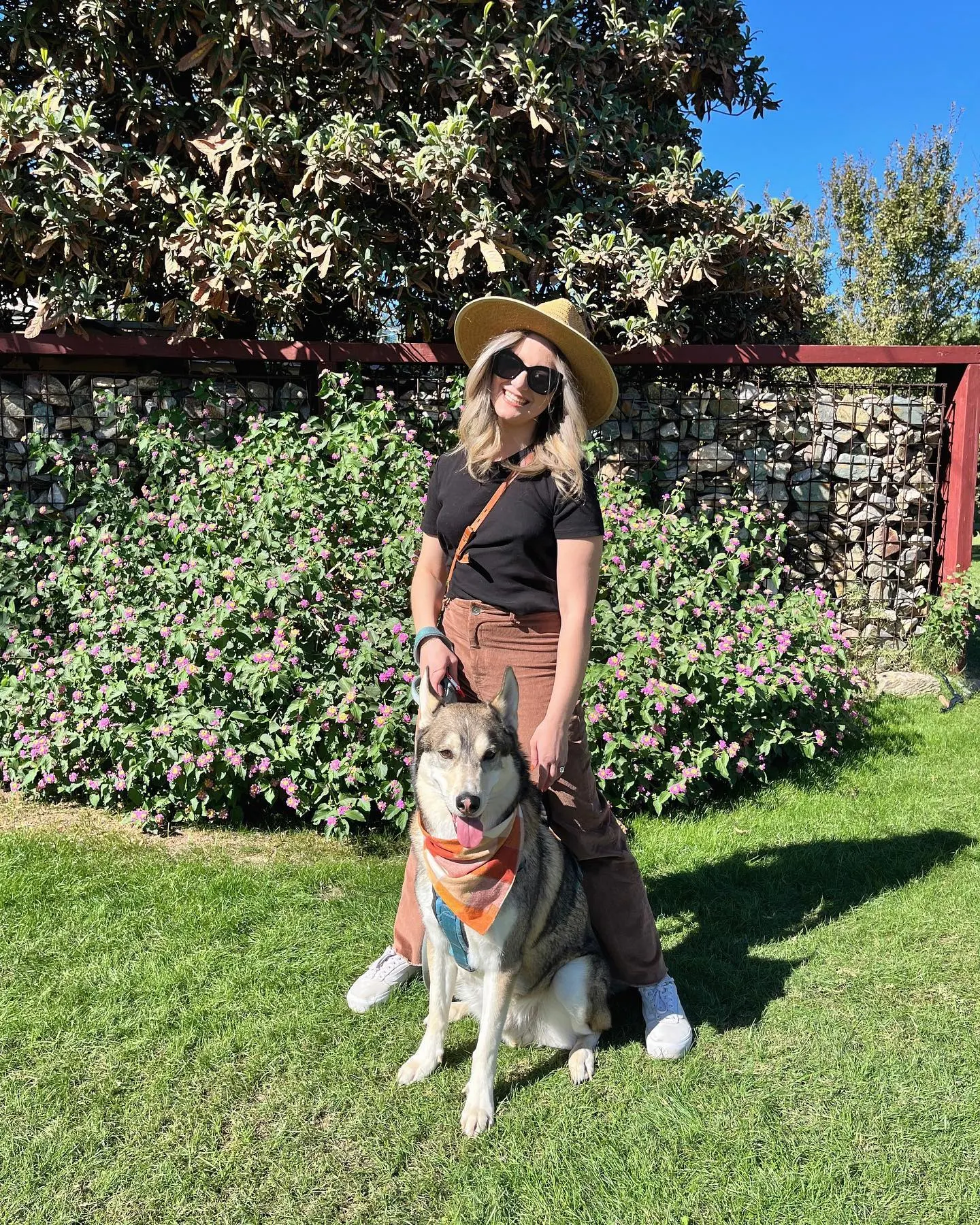 woman standing on farm in the sun with her large dog