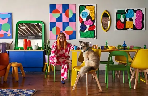 woman sits in her colorful loft with her dog
