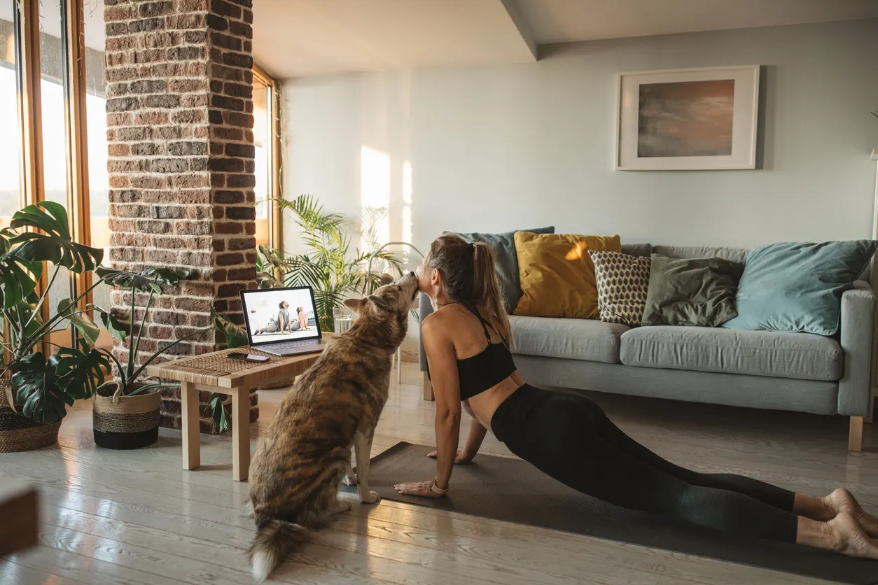 woman doing yoga with her dog in the living room