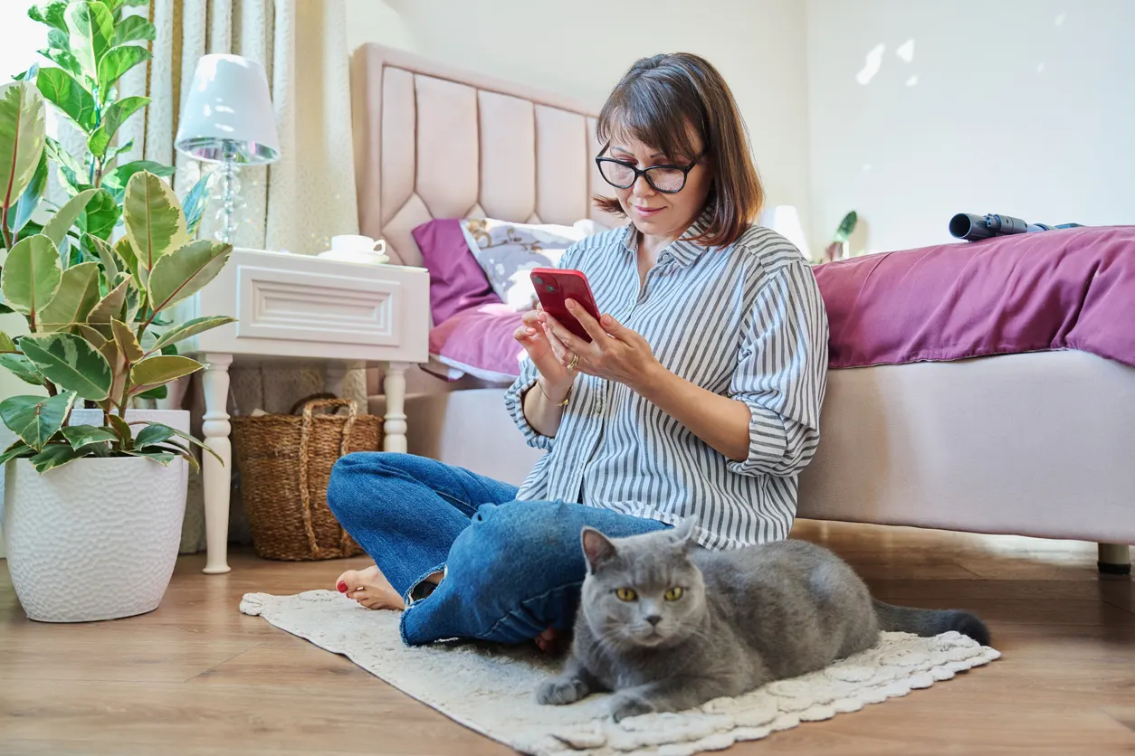Woman calculating on phone with cat nearby
