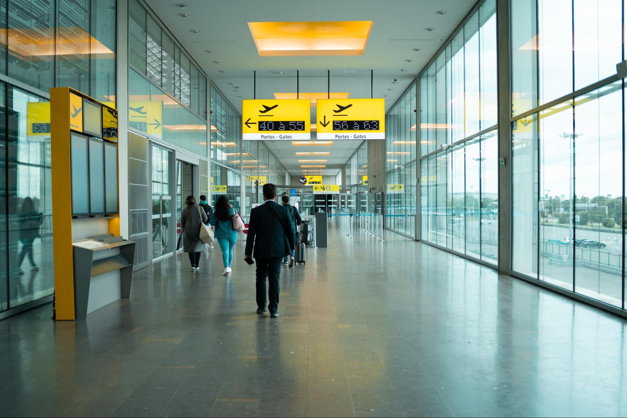 Stock image of people walking down an airport terminal hallway