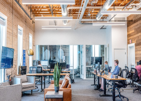 An image of a few people sitting at desks working in an office