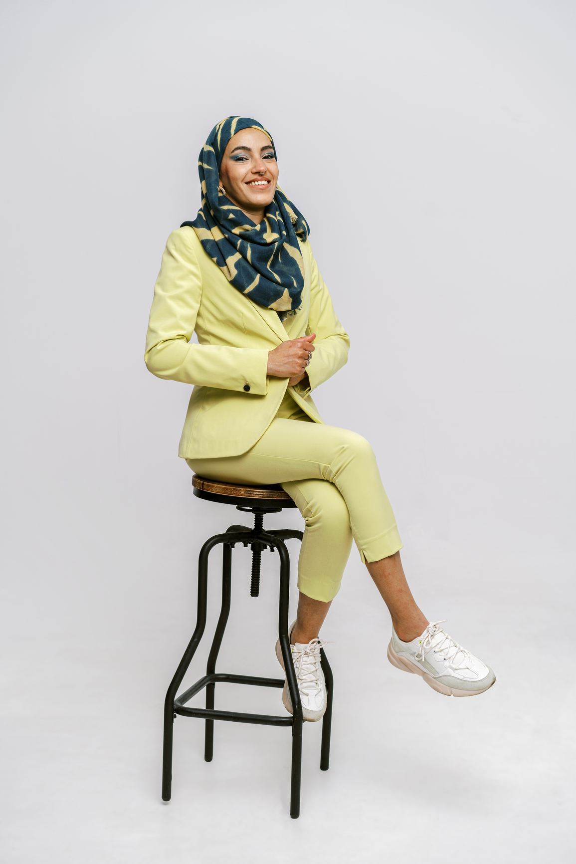 Woman in yellow pantsuit sitting on stool