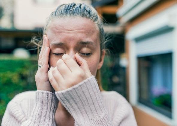 Woman pinching her nose and touching her temple