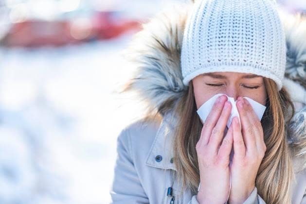 Femme qui se mouche dans un mouchoir en papier en hiver