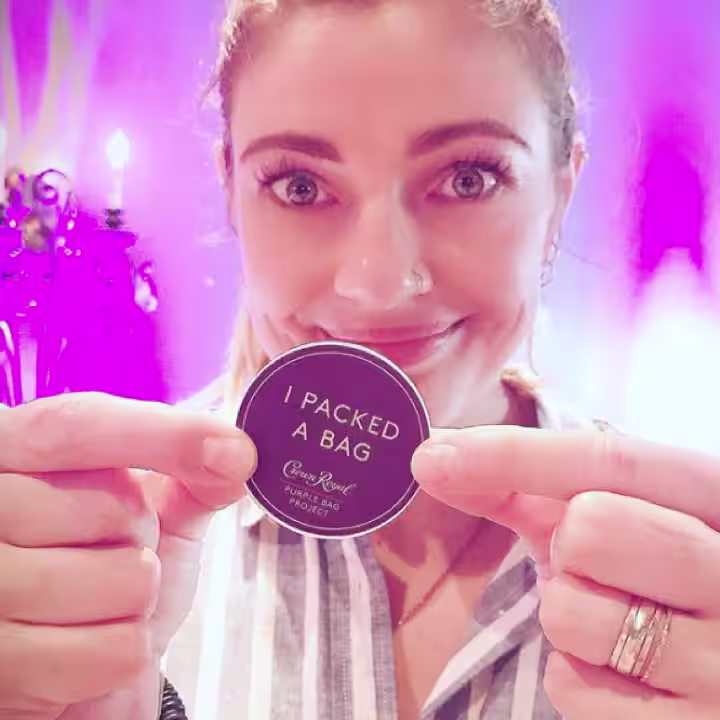 woman holding a "I packed a bag" sticker with a pink background