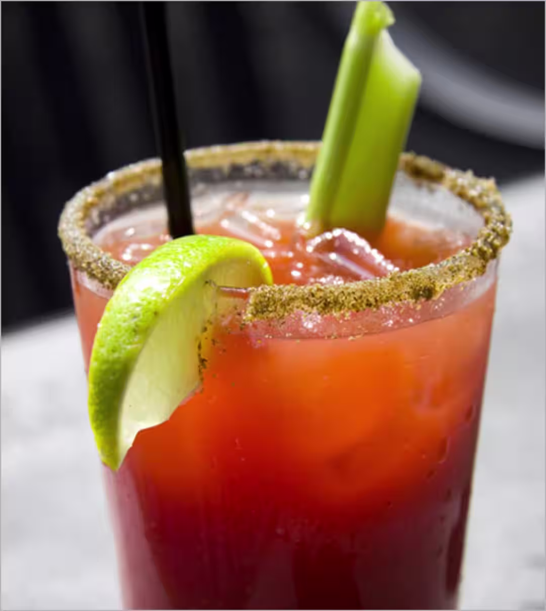 A Crown Royal Caesar cocktail garnished with a celery stick and a lime wedge