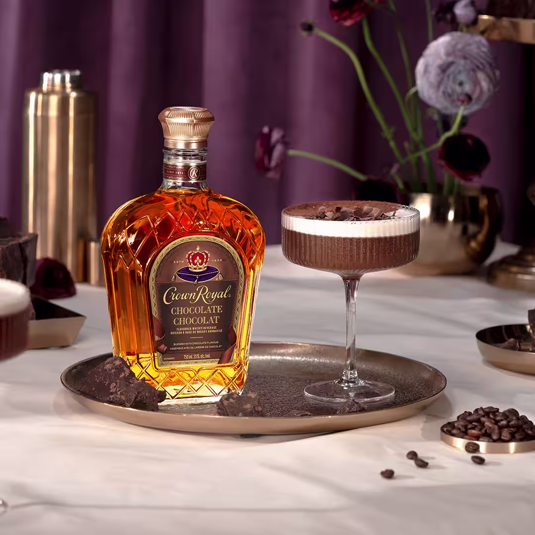 A bottle of Crown Royal Chocolate next to a chocolate martini cocktail garnished with chocolate shavings