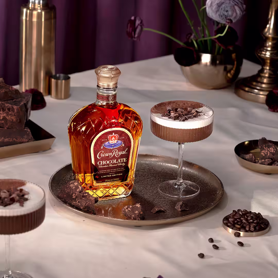 A bottle of Crown Royal Chocolate next to a chocolate martini cocktail garnished with chocolate shavings