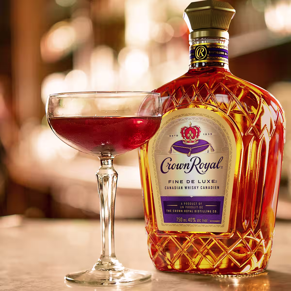 A Manhattan cocktail next to a bottle of Crown Royal DeLuxe