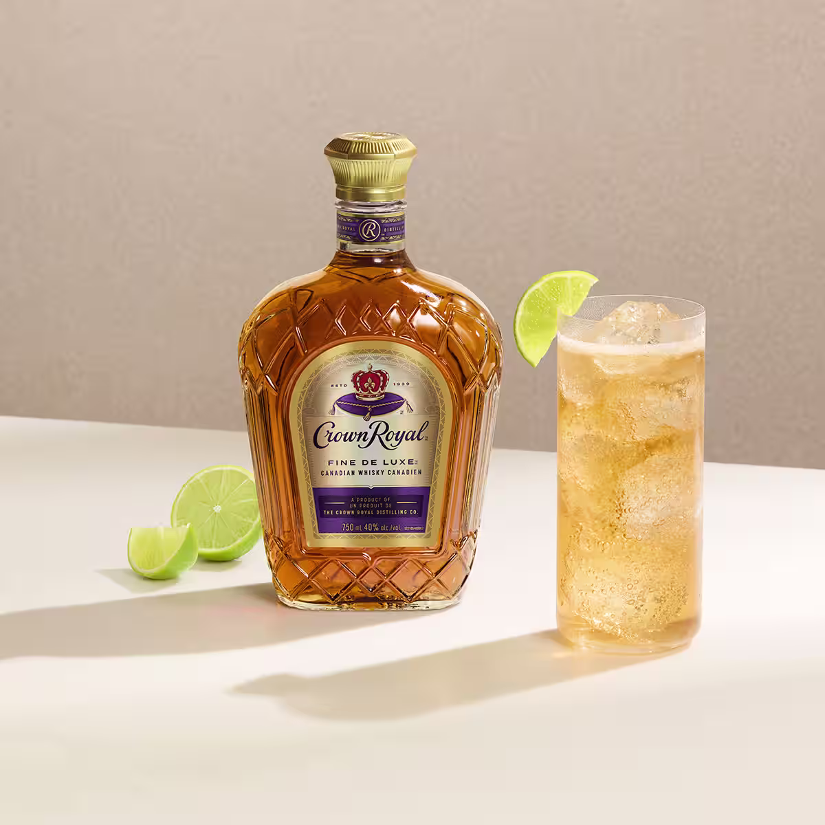 A Deluxe & Ginger cocktail on a table next to a bottle of Crown Royal Deluxe