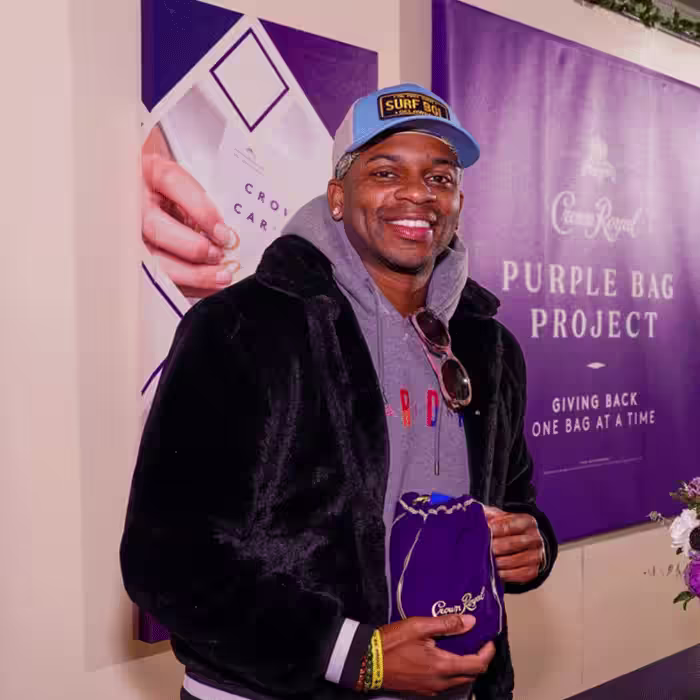 purple bag project founder holding a purple bag in front of a purple wall