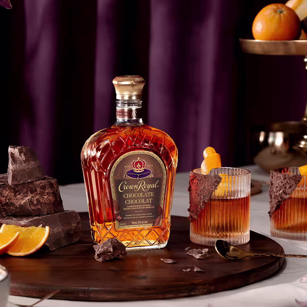 A bottle of Crown Royal Chocolate next to a chocolate whisky old fashioned cocktail