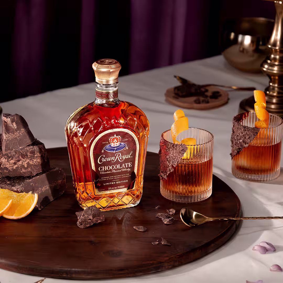 A bottle of Crown Royal Chocolate next to a chocolate whisky old fashioned cocktail