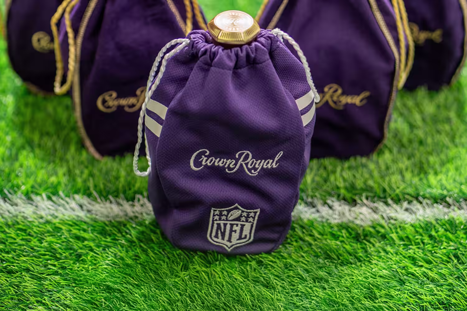 Crown Royal bottles aligned in a V formation on a football field 