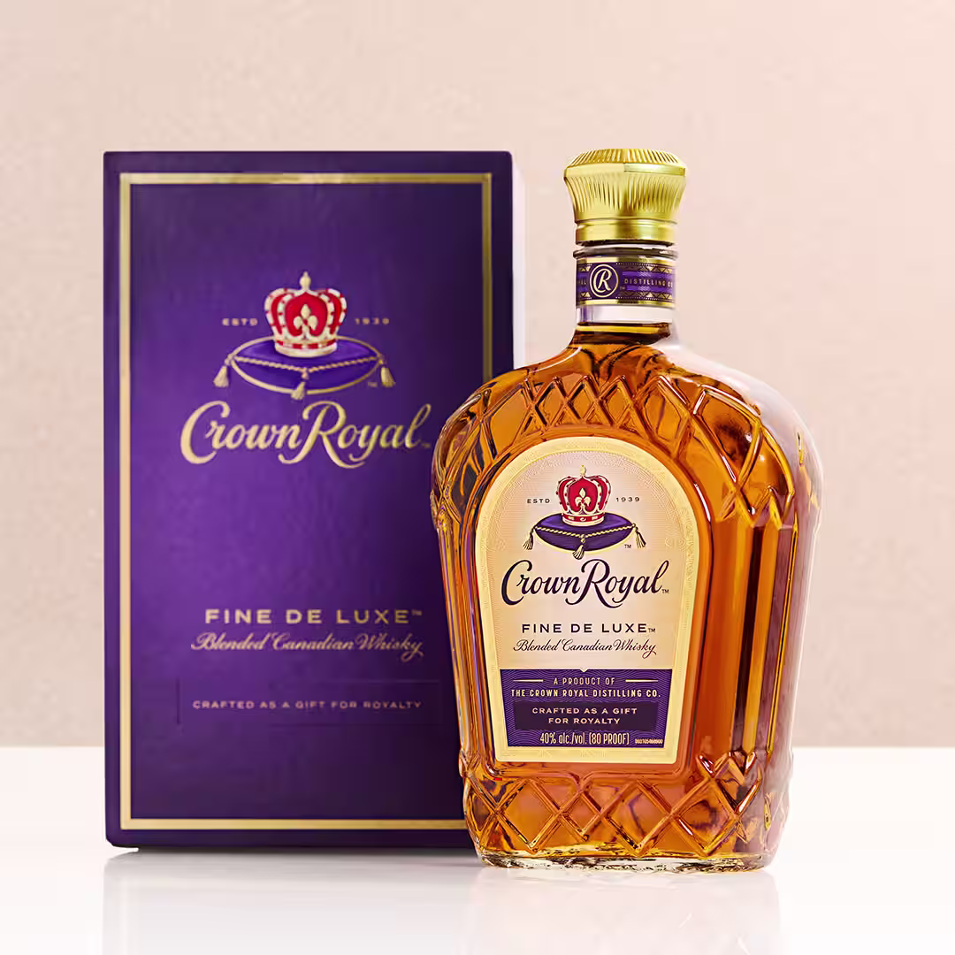 A bottle of Crown Royal next to a whisky sour cocktail