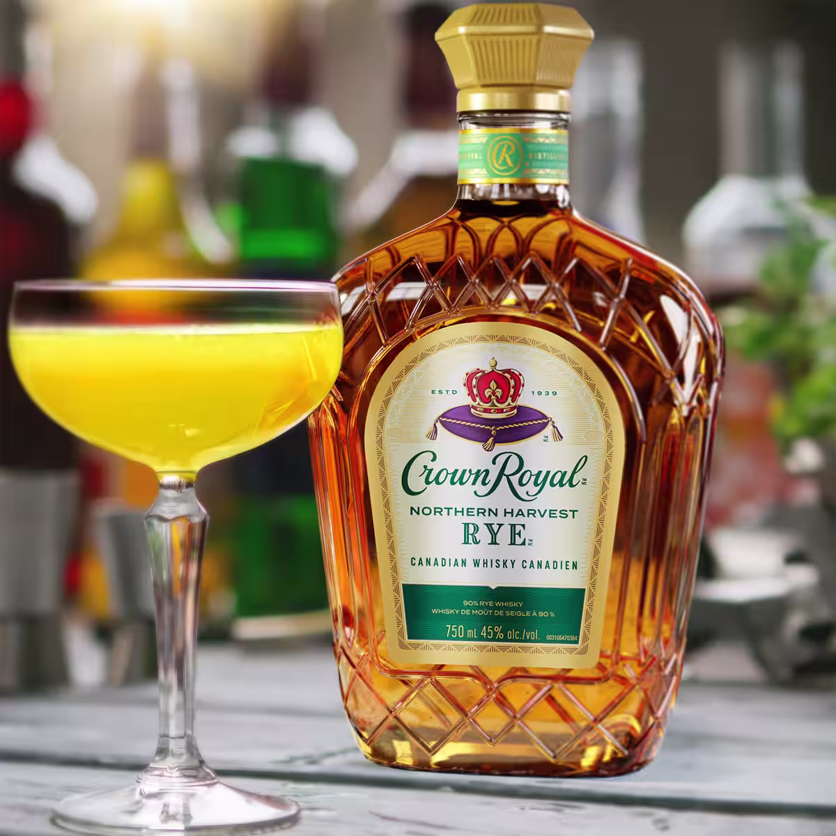 A harvest sour cocktail on table next to a bottle of Crown Royal Rye