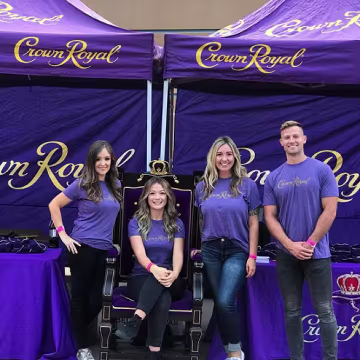 group of people standing in front of a purple tent