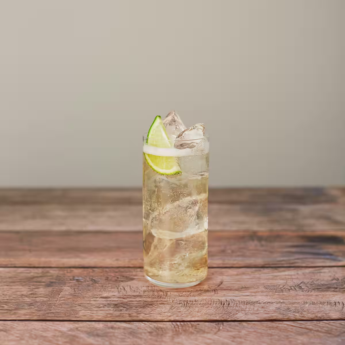 A apple and ginger cocktail garnished with a lime wedge 