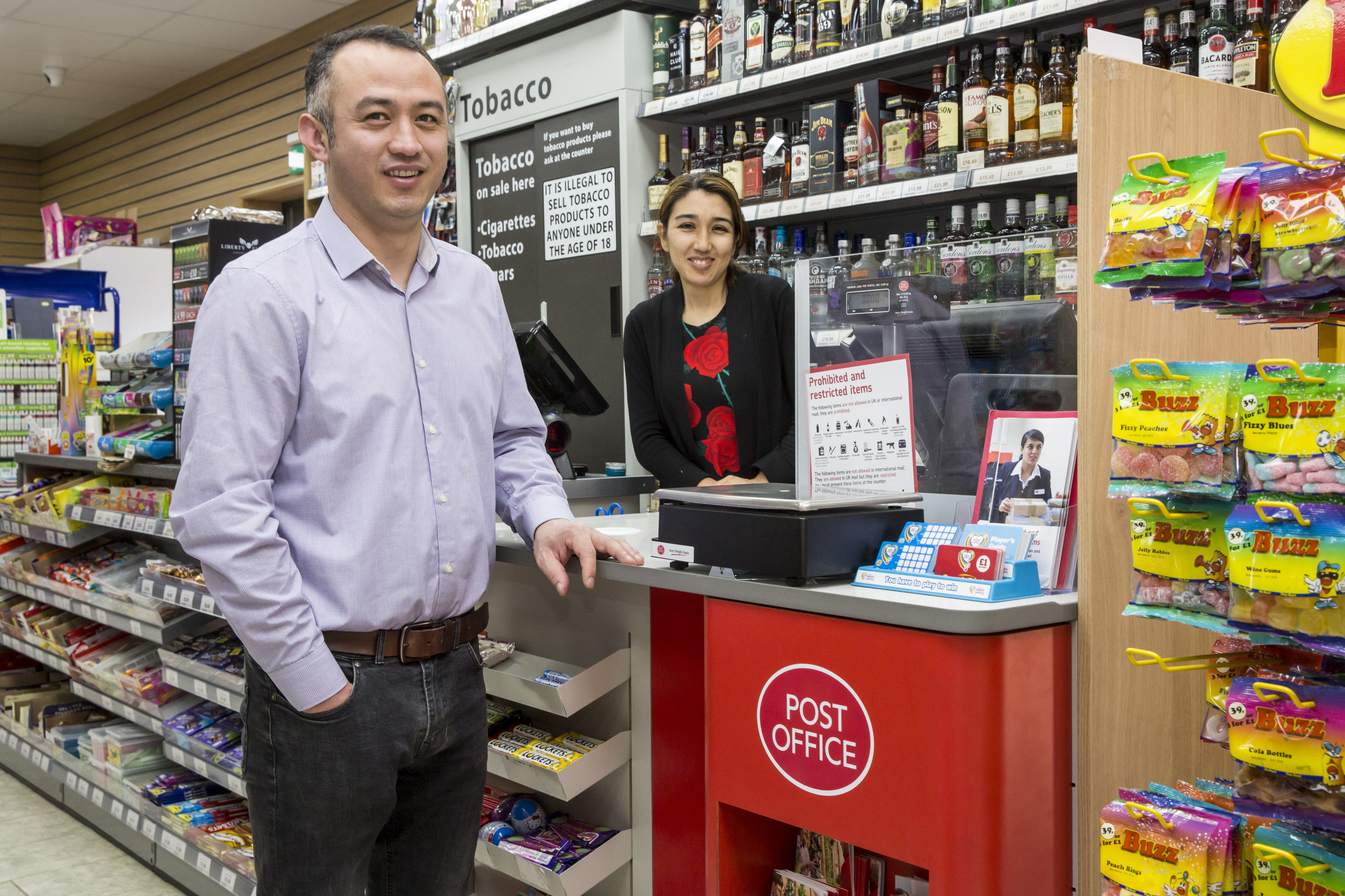 Hayat Karimi standing in front of his Post Office counter