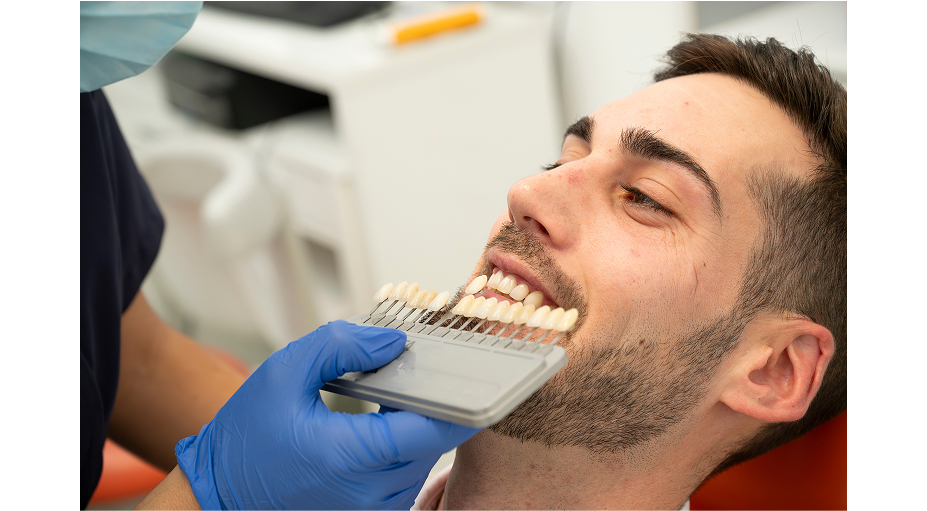 Doctor comparing tooth shades with patient
