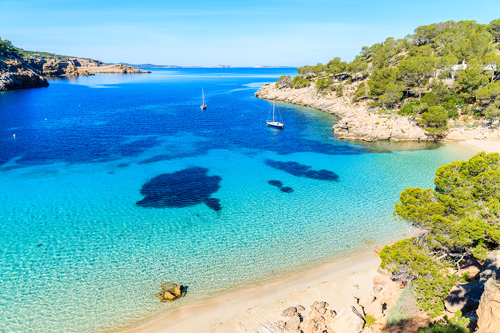 boote im blauen meer am strand ibiza