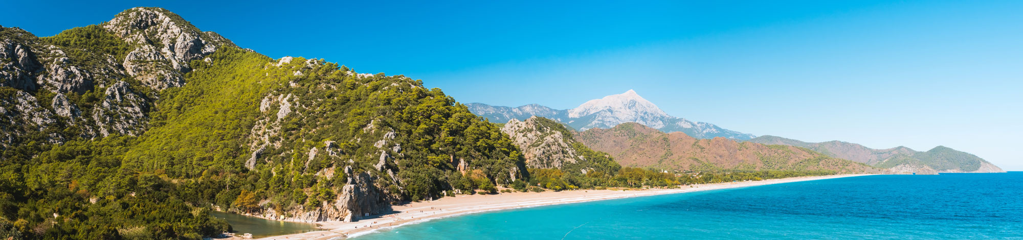 Blick auf langen Strand vor grüner Felsküste in Antalya in der Türkei