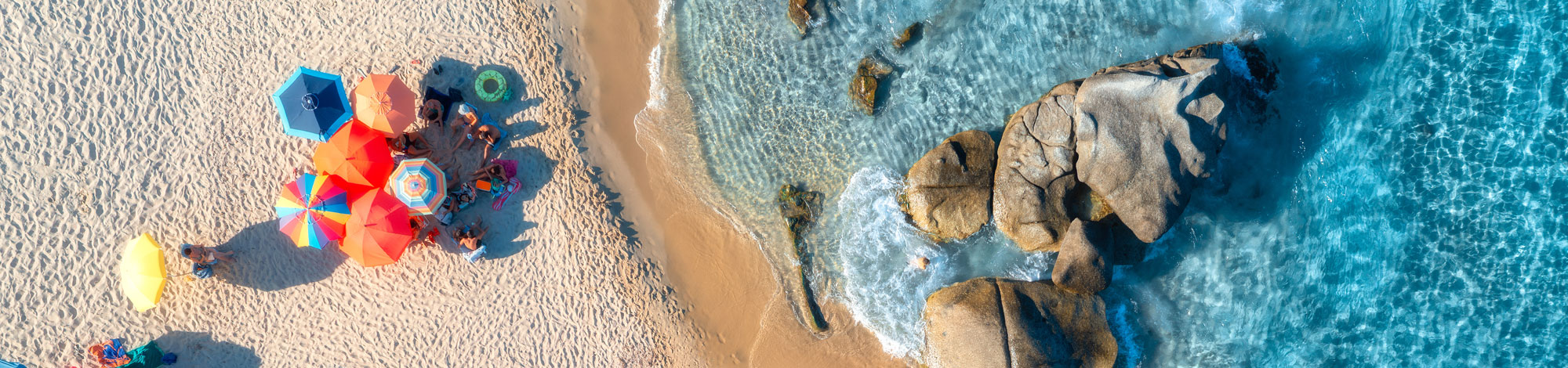 Bunte Sonnenschirme am Strand von oben