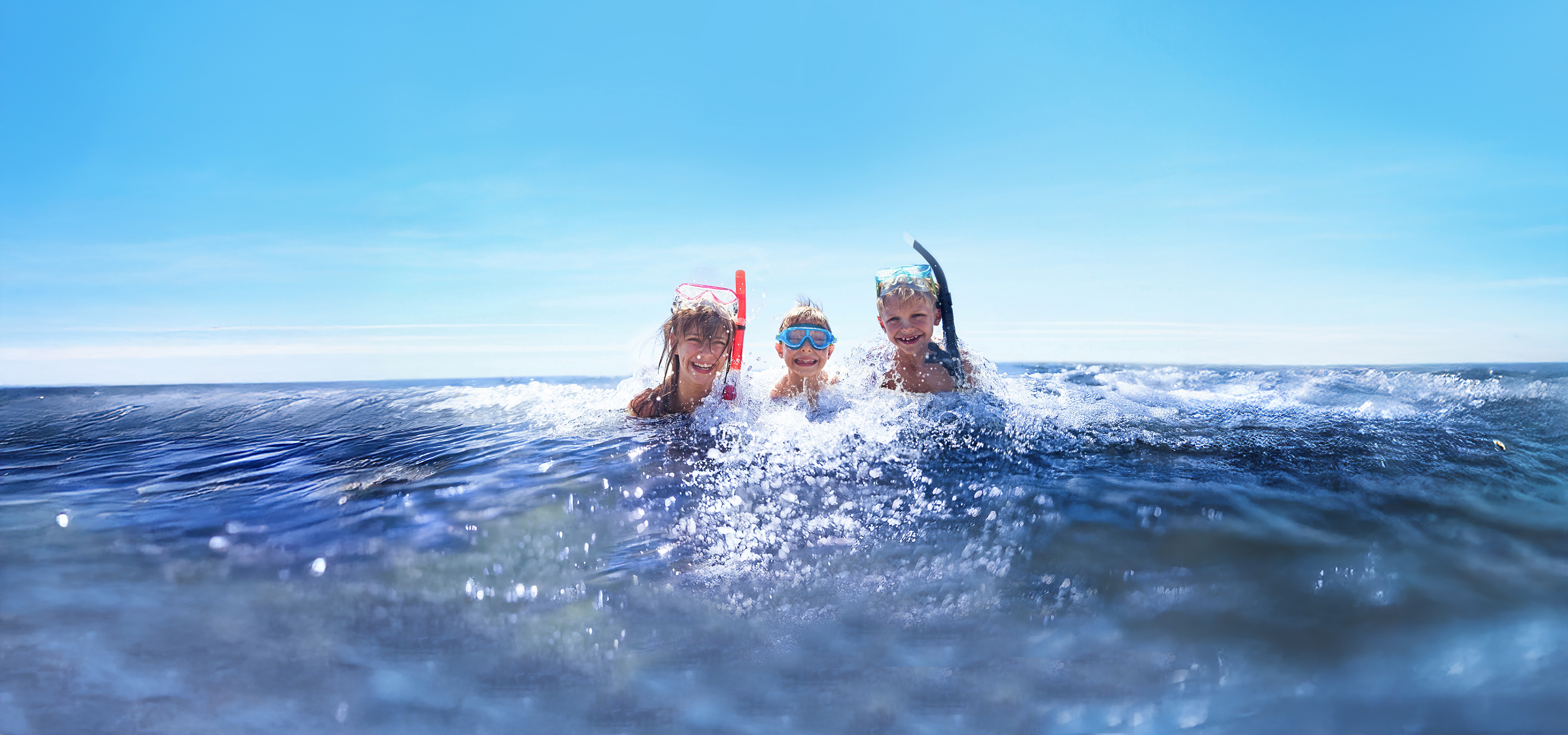 Familie mit Flossen und Schnorchel am Strand