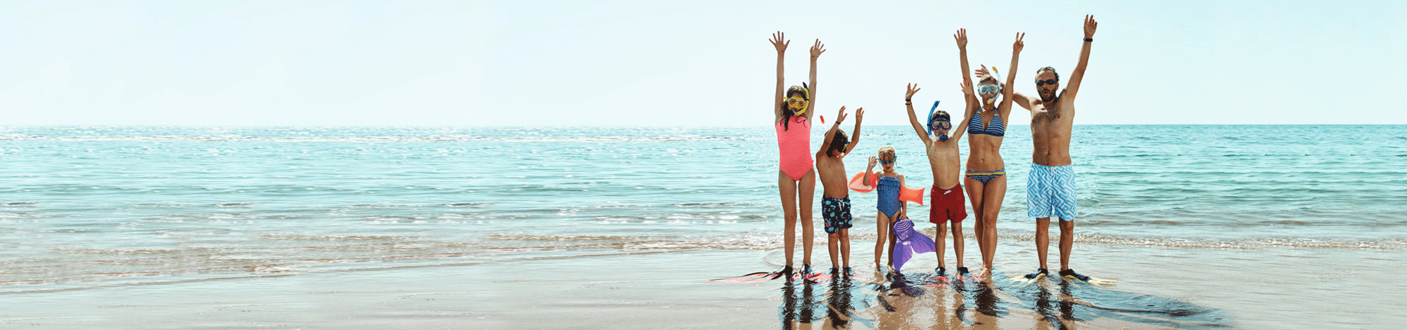 Familie mit Flossen und Schnorchel am Strand