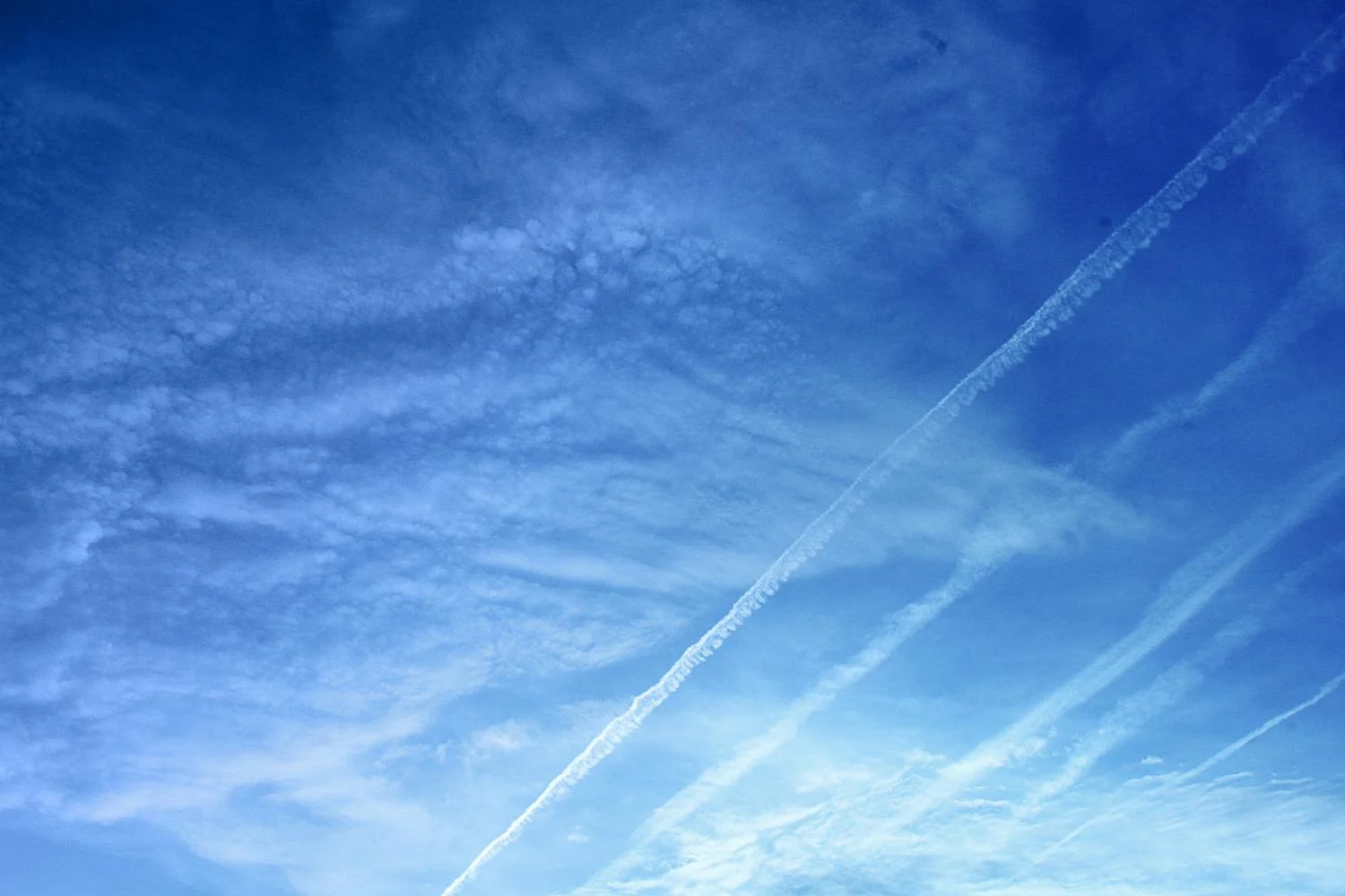 Blue sky, clouds and contrails. 