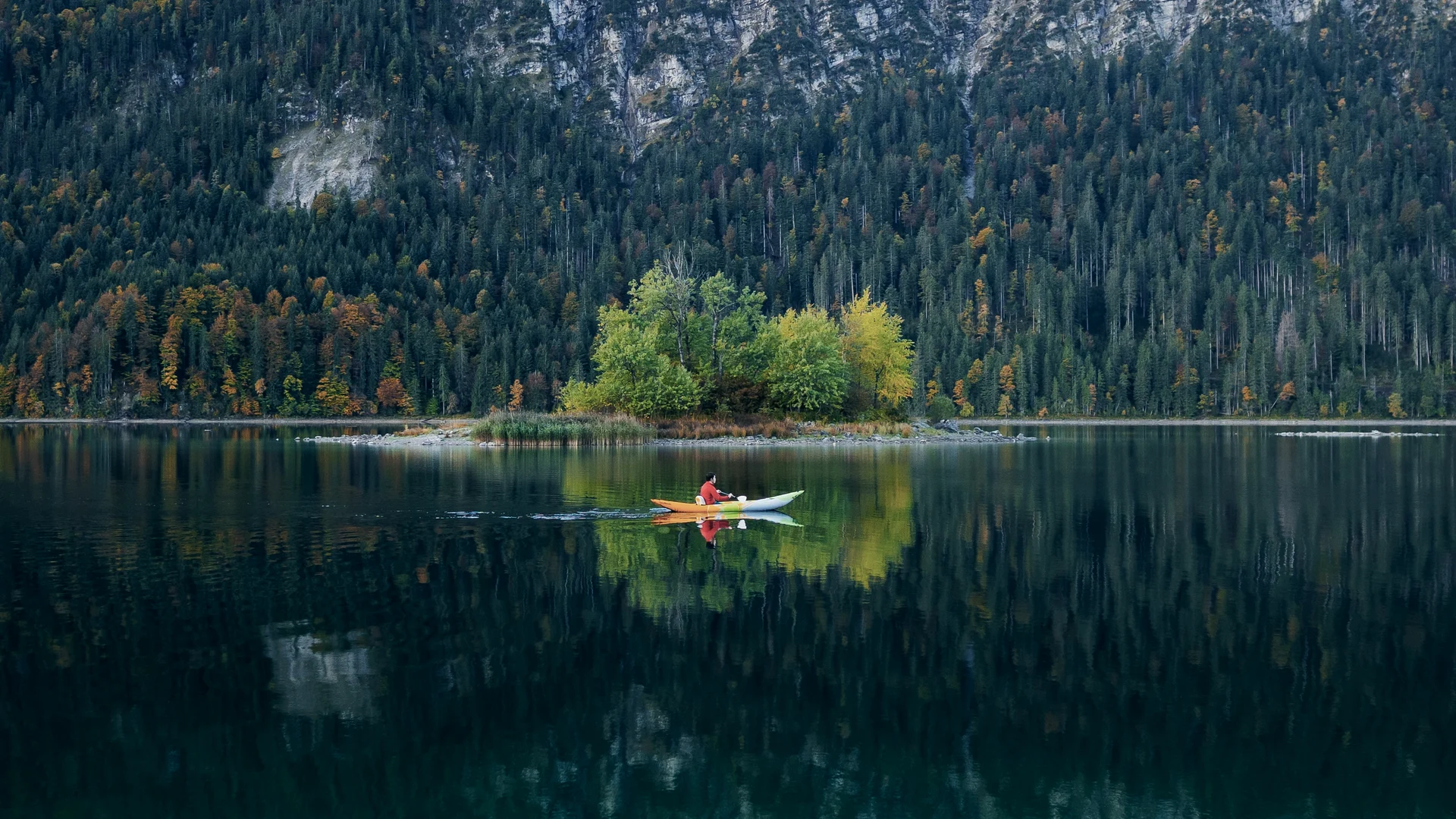 Man kayaking on lake in autumn. 