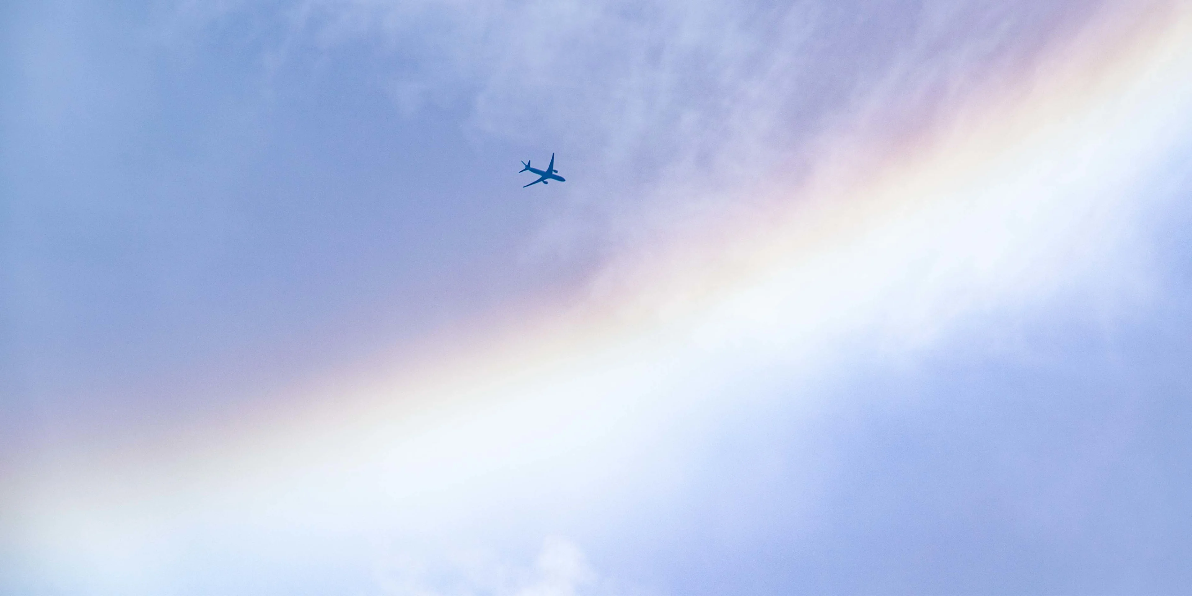 Aeroplane flyinc across the sky with a rainbow