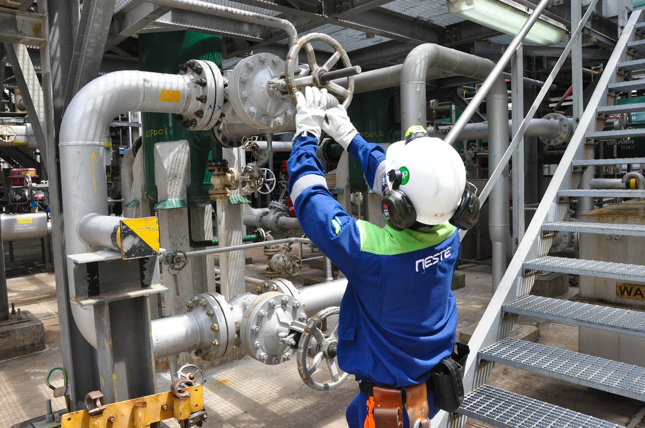 Neste worker turning a valve in a refinery