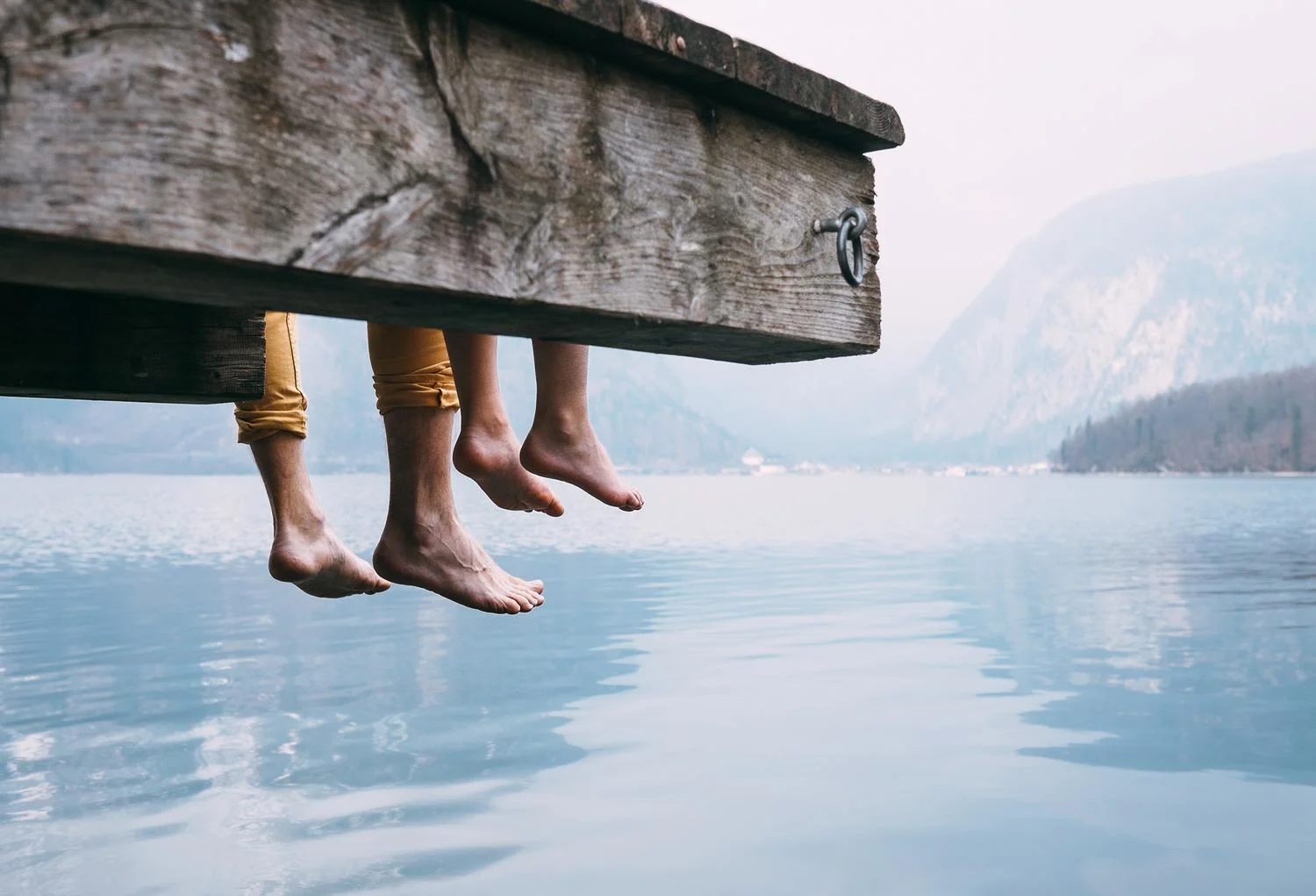 People are sitting on the pier by the lake