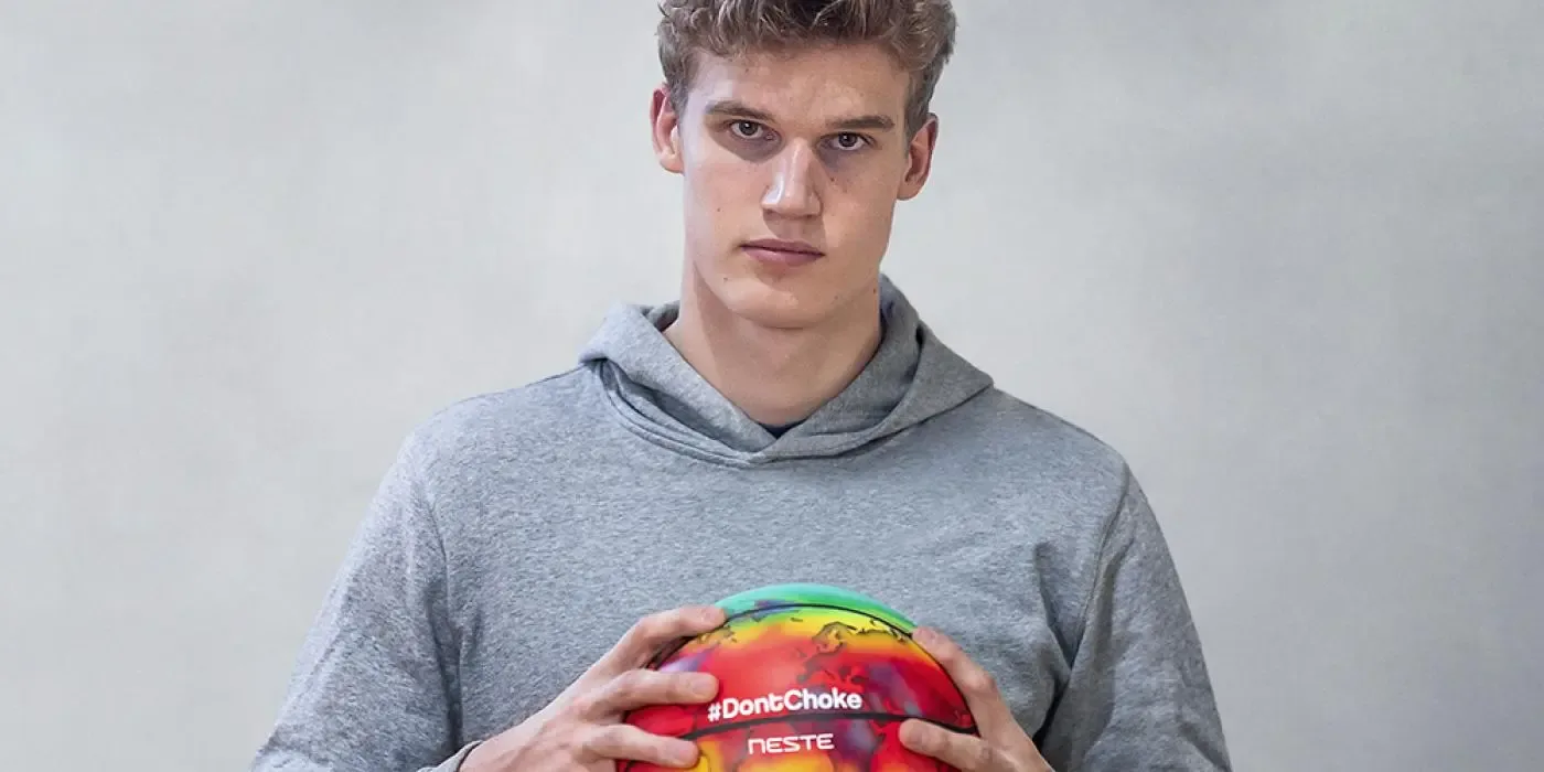 Photo of Lauri Markkanen holding a basketball with Neste's logo and #DontChoke printed on it.