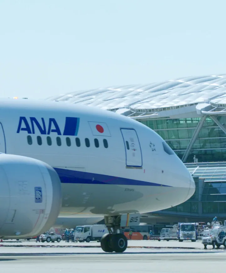 Front section of an airplane on the tarmac, in front of an airport terminal.