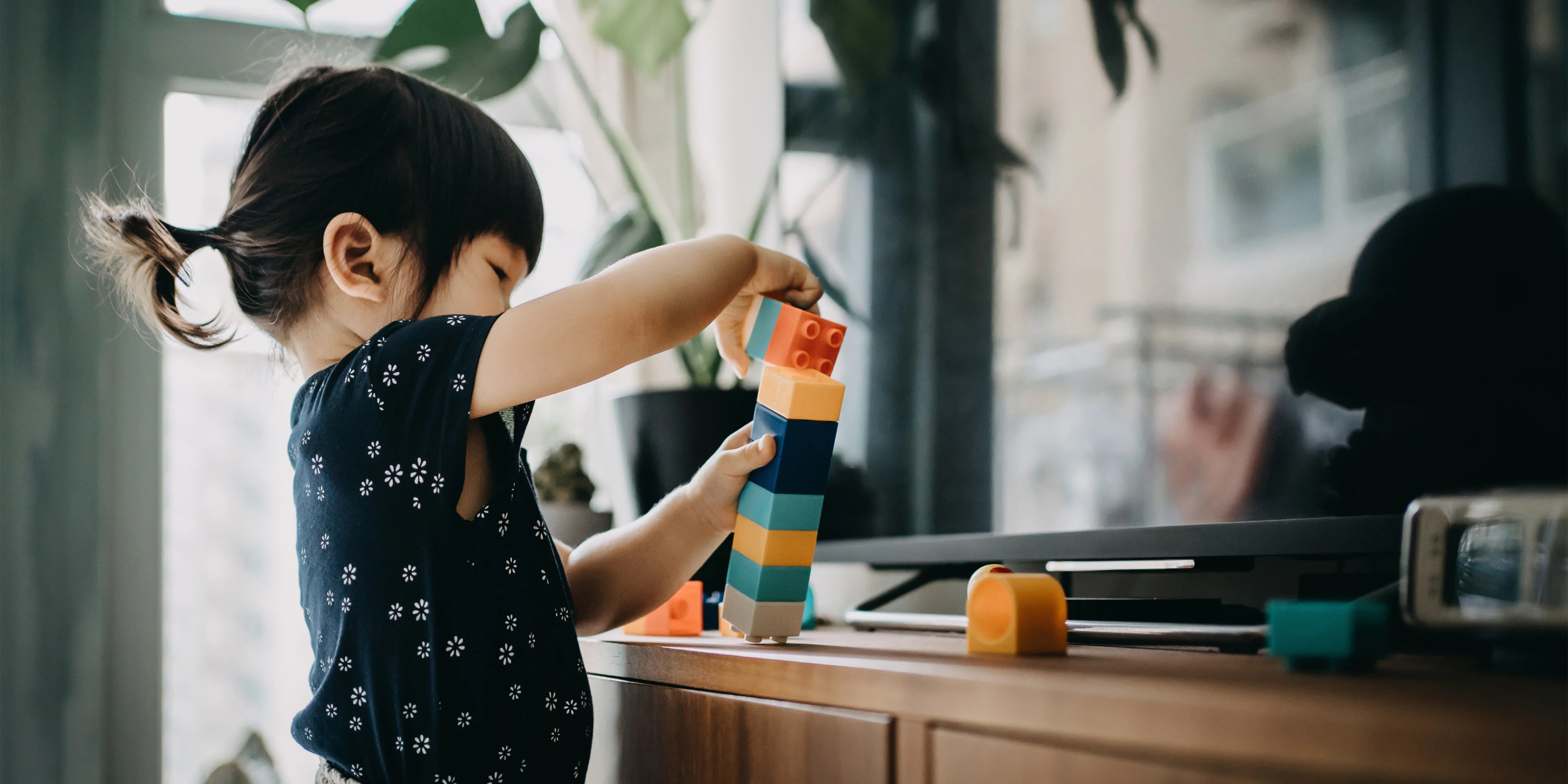 Toddler playing with colorful building blocks | Neste article