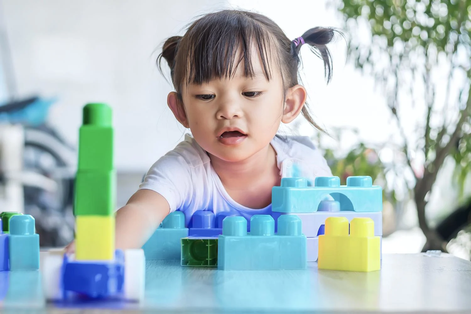 Toddler playing with colorful building blocks | Neste article