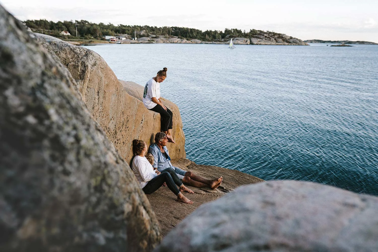 People sitting on a rock by the water.
